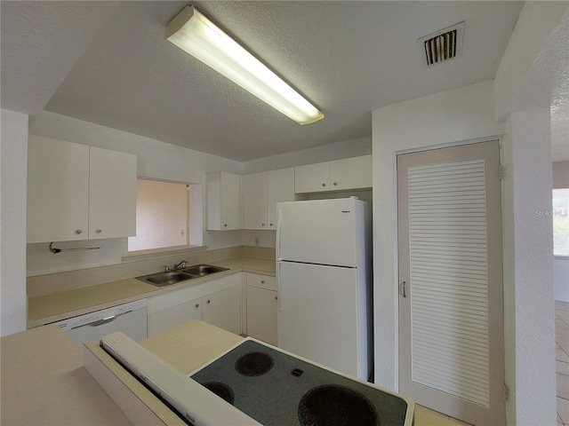 kitchen featuring light countertops, visible vents, white cabinetry, a sink, and white appliances