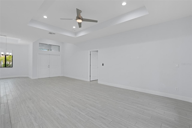 unfurnished room featuring light wood-type flooring, baseboards, and a tray ceiling