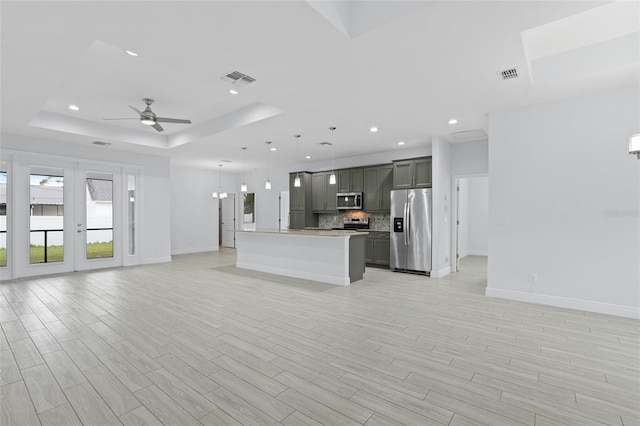 interior space featuring appliances with stainless steel finishes, open floor plan, and a raised ceiling