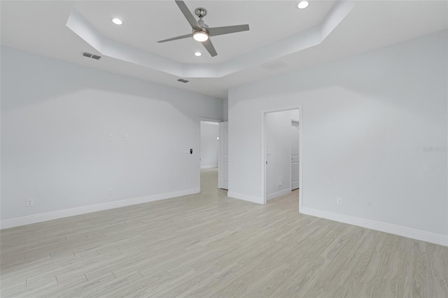 unfurnished room with recessed lighting, visible vents, baseboards, a tray ceiling, and light wood finished floors