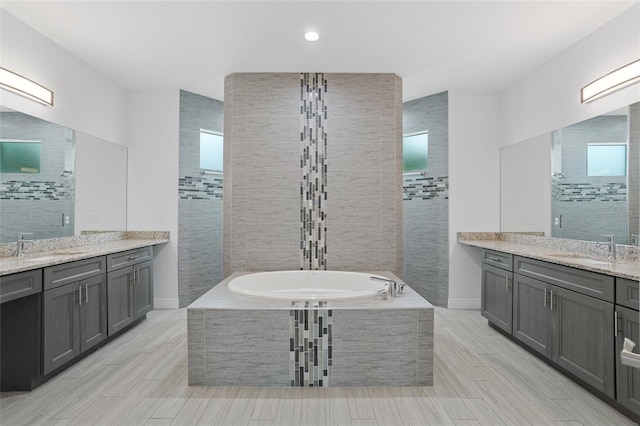 bathroom featuring two vanities, a sink, and a bath