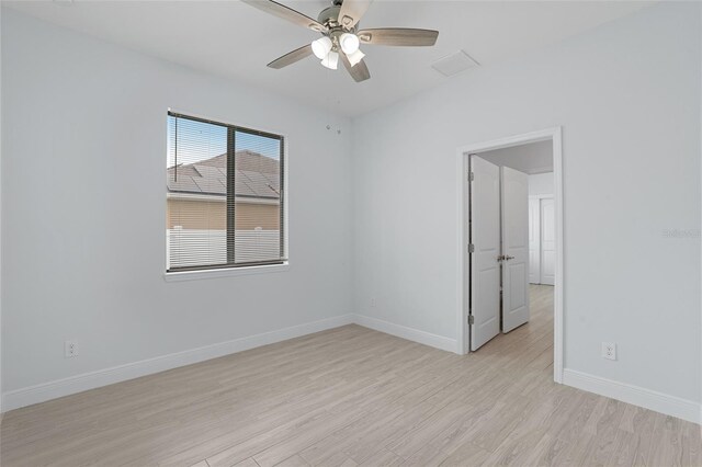 empty room with light wood finished floors, visible vents, baseboards, and ceiling fan