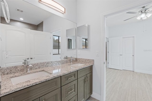 bathroom with double vanity, baseboards, a sink, and wood finished floors