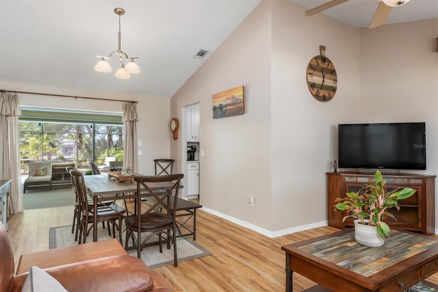 dining space featuring visible vents, a notable chandelier, baseboards, light wood-style floors, and lofted ceiling