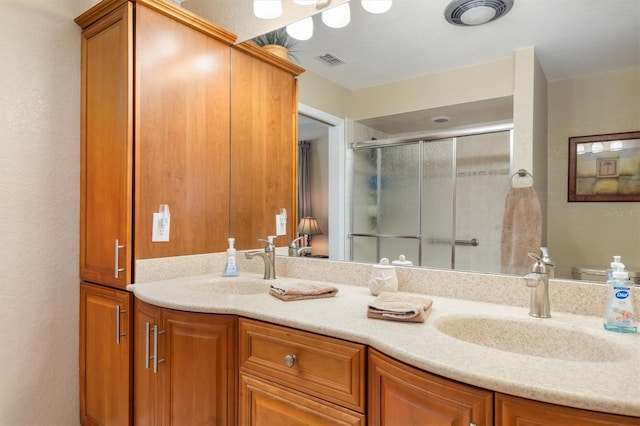 full bath featuring a sink, visible vents, a stall shower, and double vanity