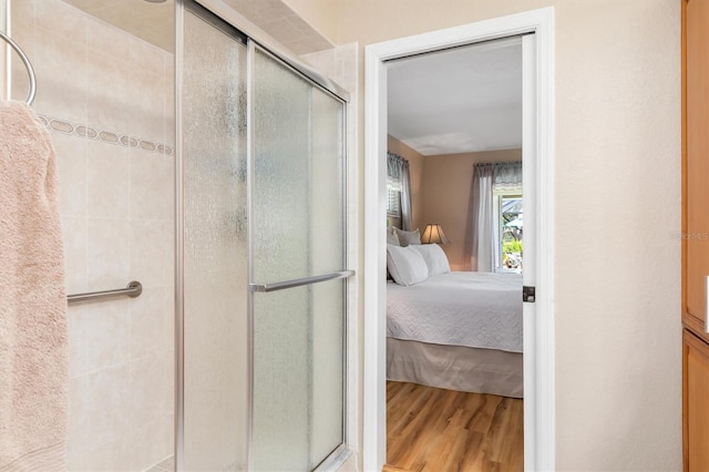 bathroom featuring ensuite bath, wood finished floors, and a stall shower