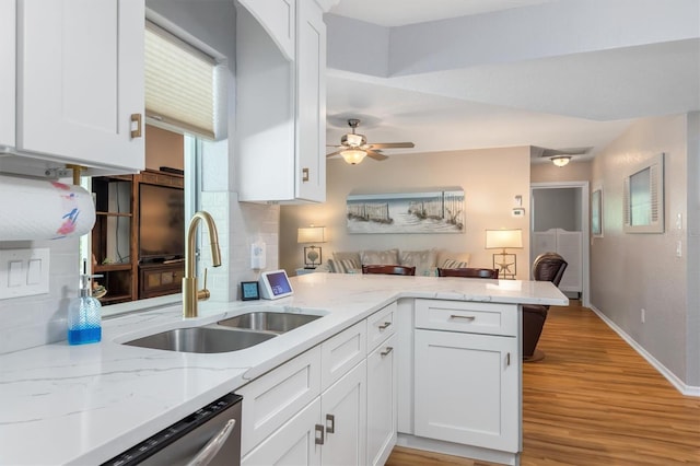 kitchen with backsplash, dishwasher, a peninsula, white cabinets, and a sink