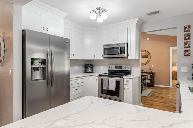 kitchen with visible vents, light stone countertops, appliances with stainless steel finishes, and white cabinetry