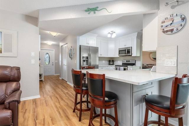 kitchen featuring a peninsula, white cabinets, open floor plan, and stainless steel appliances