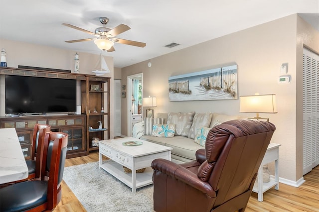 living area with visible vents, baseboards, ceiling fan, and wood finished floors