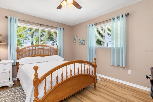 bedroom featuring multiple windows, baseboards, light wood-type flooring, and ceiling fan