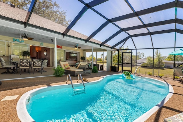 pool featuring glass enclosure, a ceiling fan, and a patio