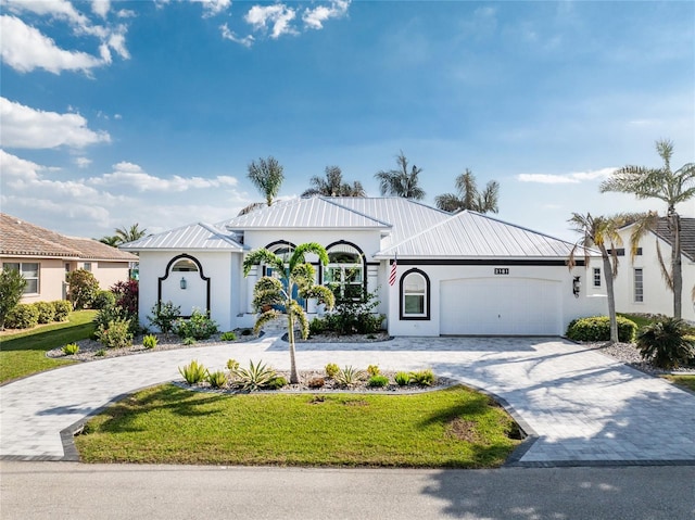 2181 Via Seville, Punta Gorda, FL 33950 - view of front of house with metal roof, a garage, decorative driveway, stucco siding, and a front yard