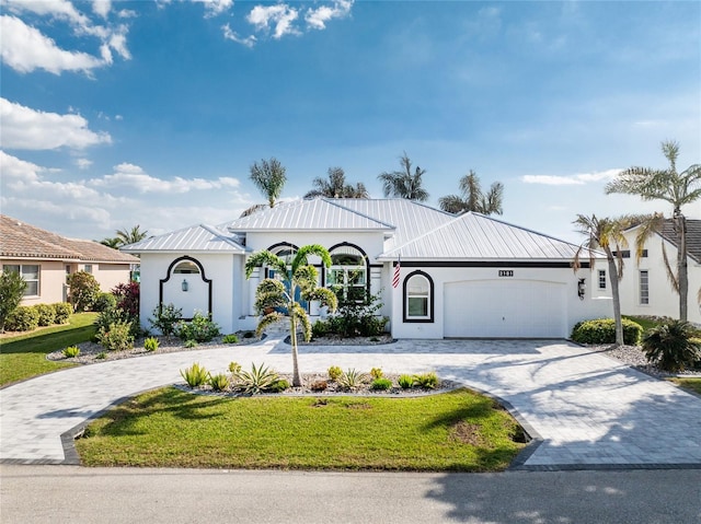 view of front of house with metal roof, a garage, decorative driveway, stucco siding, and a front yard