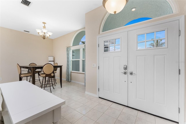 entryway featuring a chandelier, visible vents, baseboards, and light tile patterned floors