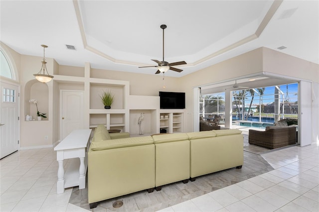 living area featuring light tile patterned floors, visible vents, and a tray ceiling