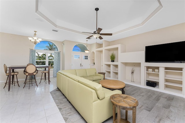 living area featuring light tile patterned floors, built in shelves, a raised ceiling, and visible vents