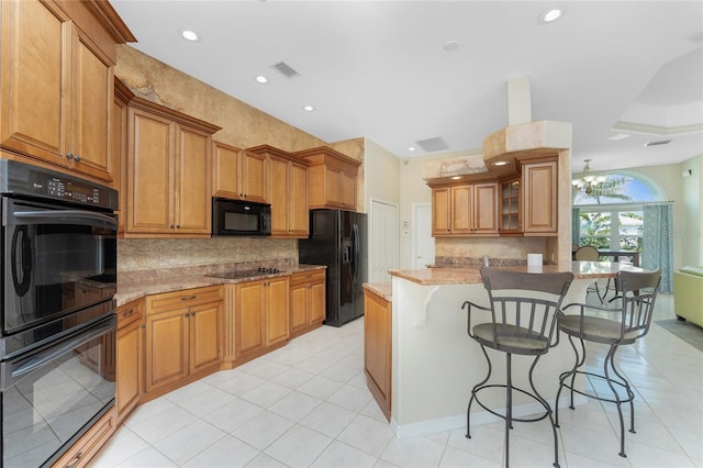 kitchen featuring light stone countertops, visible vents, brown cabinets, black appliances, and a kitchen bar