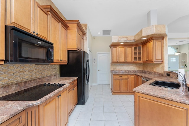 kitchen with light tile patterned floors, visible vents, brown cabinets, black appliances, and a sink