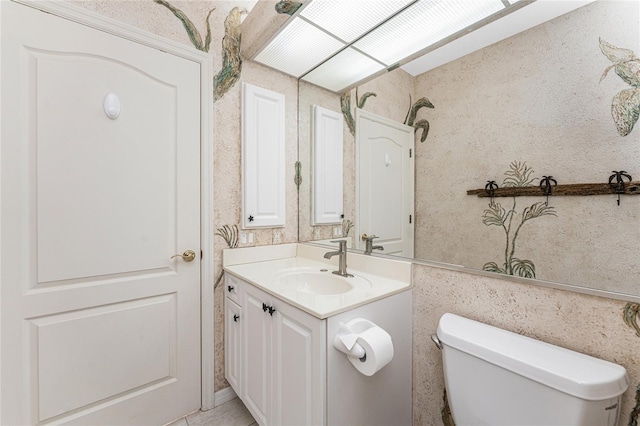 half bath featuring toilet, wallpapered walls, and vanity