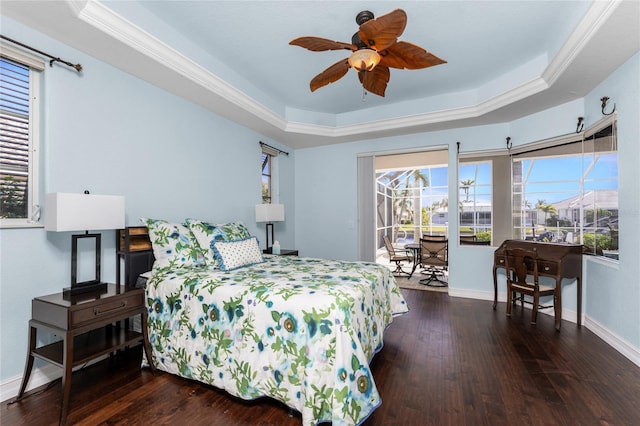 bedroom featuring wood finished floors, multiple windows, a raised ceiling, and access to exterior