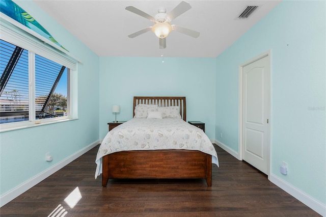 bedroom with ceiling fan, wood finished floors, visible vents, and baseboards