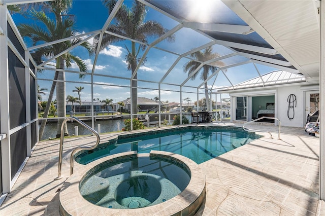 view of pool featuring a patio, glass enclosure, a water view, and a pool with connected hot tub