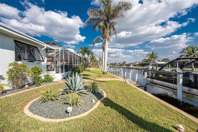 view of yard featuring a dock, glass enclosure, a water view, and boat lift