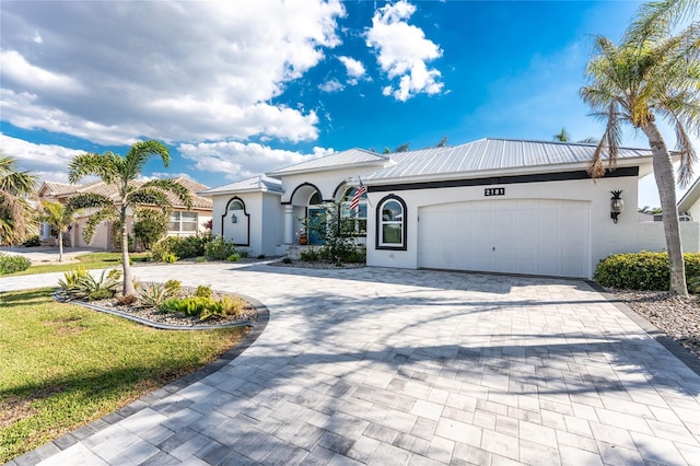 view of front of property with an attached garage, metal roof, decorative driveway, and stucco siding