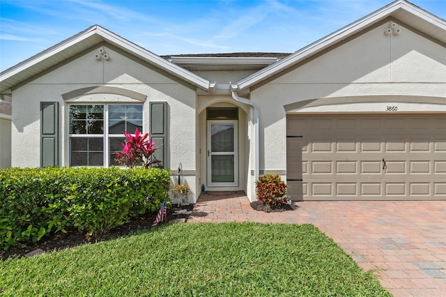 ranch-style house with decorative driveway, an attached garage, and stucco siding