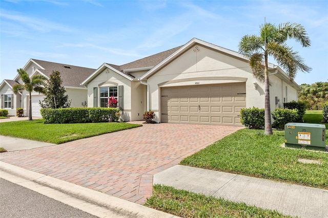 single story home featuring decorative driveway, an attached garage, a front yard, and stucco siding