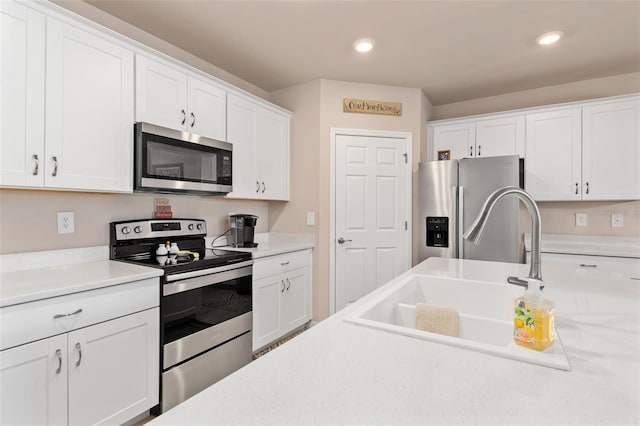 kitchen featuring recessed lighting, stainless steel appliances, a sink, white cabinetry, and light countertops