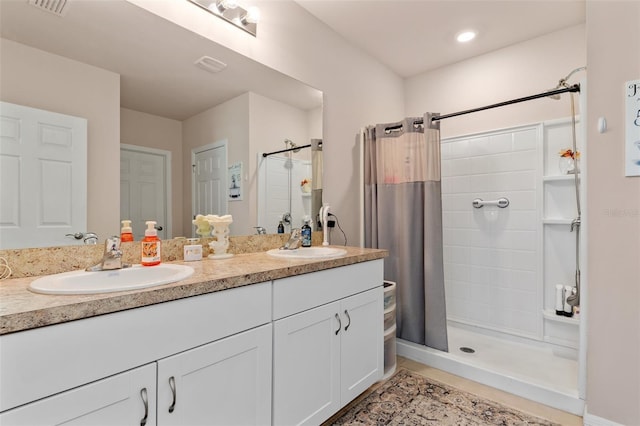 bathroom featuring double vanity, a stall shower, visible vents, and a sink