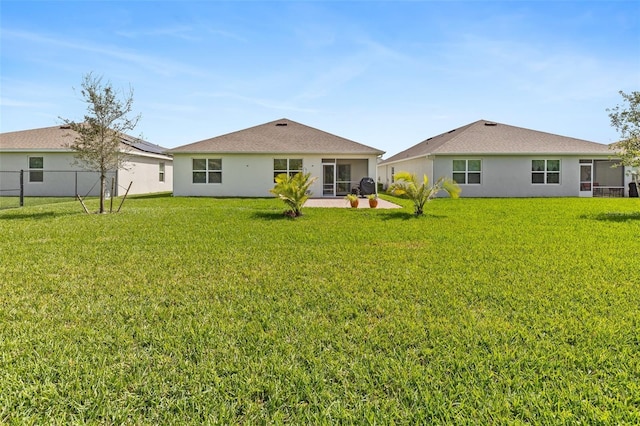 rear view of house with a yard, a patio, fence, and stucco siding