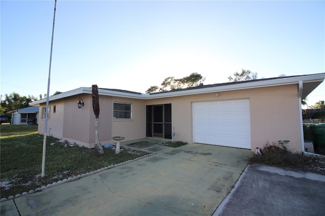 single story home featuring a garage, concrete driveway, and a front yard