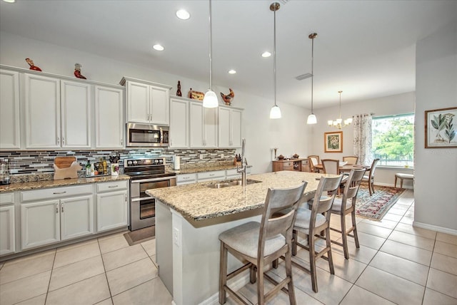 kitchen featuring stainless steel appliances, light tile patterned flooring, a sink, and backsplash