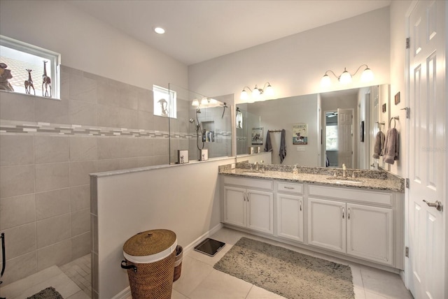 bathroom with double vanity, a walk in shower, a sink, and tile patterned floors