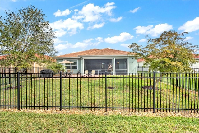 view of front of home featuring stucco siding, a sunroom, a fenced backyard, a tiled roof, and a front lawn