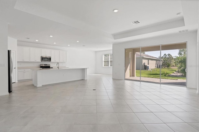 unfurnished living room featuring a tray ceiling, light tile patterned flooring, visible vents, and recessed lighting