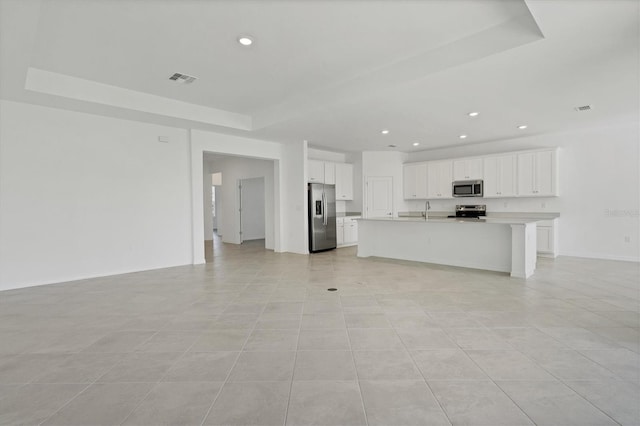 unfurnished living room featuring recessed lighting, a raised ceiling, a sink, and baseboards