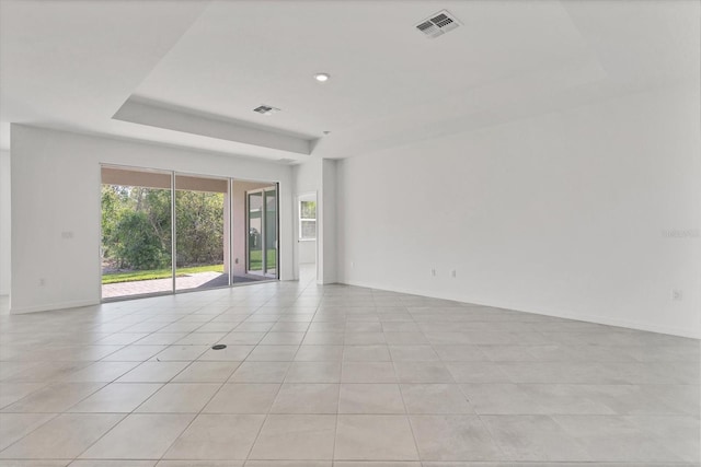 spare room with a raised ceiling, visible vents, baseboards, and light tile patterned floors