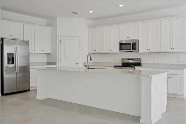 kitchen with a sink, white cabinetry, light countertops, appliances with stainless steel finishes, and an island with sink