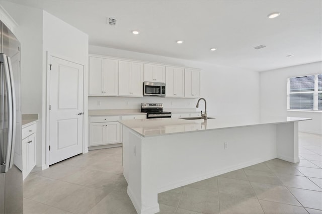 kitchen featuring a center island with sink, light countertops, visible vents, appliances with stainless steel finishes, and a sink