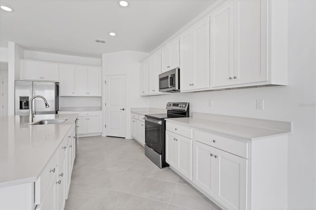 kitchen with light countertops, appliances with stainless steel finishes, a sink, and white cabinets