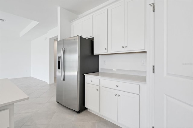 kitchen with light countertops, visible vents, white cabinets, light tile patterned flooring, and stainless steel fridge