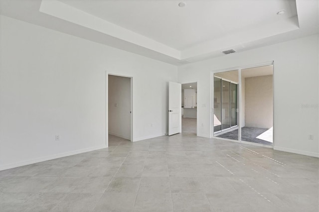 unfurnished bedroom featuring a raised ceiling, visible vents, and baseboards