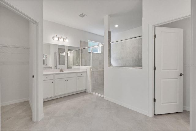 bathroom featuring visible vents, a spacious closet, a stall shower, vanity, and baseboards