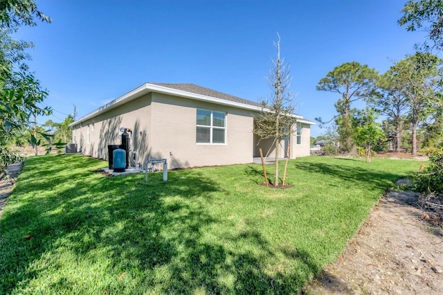 rear view of house featuring a yard and stucco siding