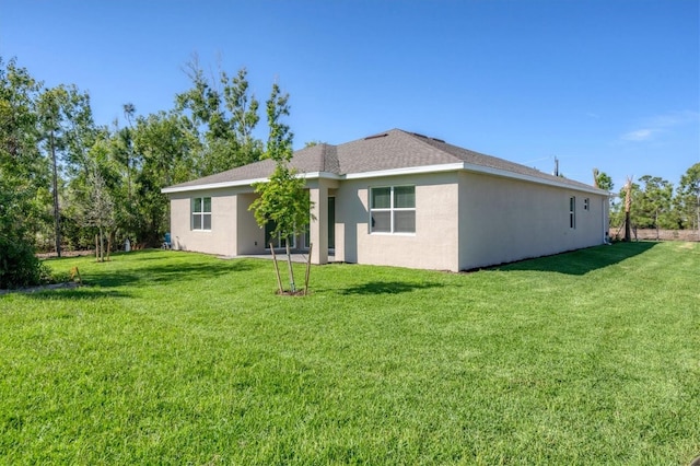 rear view of house with a yard and stucco siding