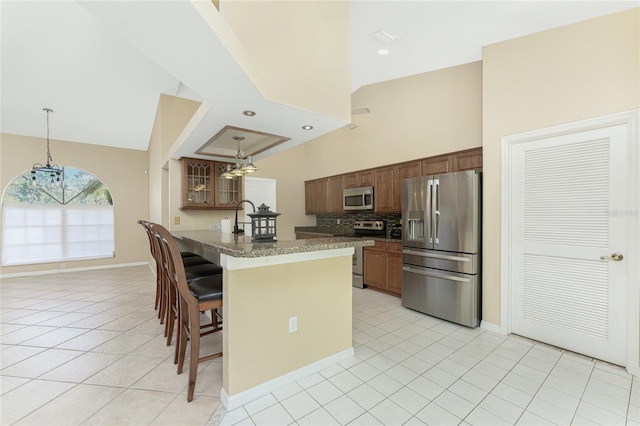 16571 Cape Horn Blvd, Punta Gorda, FL 33955 - kitchen featuring a breakfast bar area, light tile patterned floors, appliances with stainless steel finishes, backsplash, and a chandelier